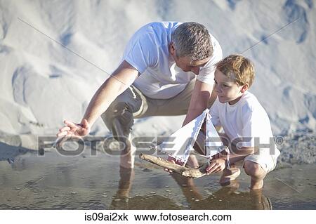 Father and son playing toy boat on beach View Large Photo Image Stock Image - Father and son playing toy boat on beach. Fotosearch