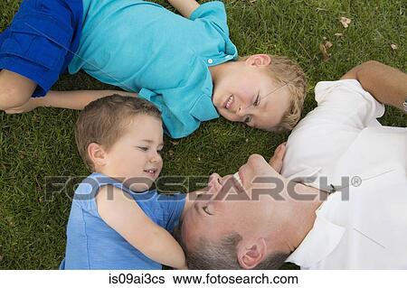 Father and sons playing on grass View Large Photo Image Stock Photograph - Father and sons playing on grass. Fotosearch