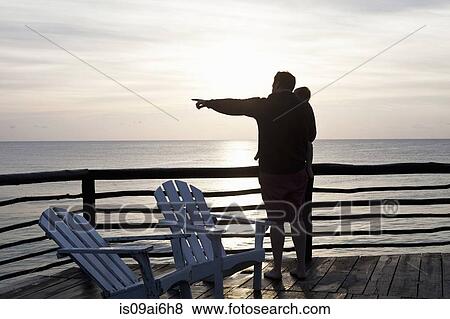 Stock Photo - Father holding daughter and pointing out to sea in Tulum, Mexico. Fotosearch