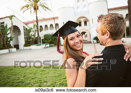 Stock Photograph - Female graduate hugging man. Fotosearch