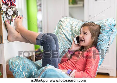 Stock Photograph - Girl sitting on armchair on phonecall. Fotosearch