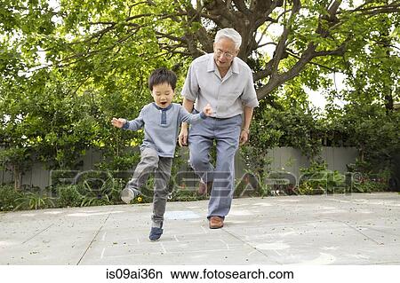 Picture - Grandfather playing hopscotch with grandson. Fotosearch
