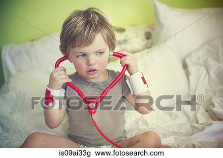 Male toddler listening to toy stethoscope on bed View Large Photo Image Stock Image - Male toddler listening to toy stethoscope on bed. Fotosearch