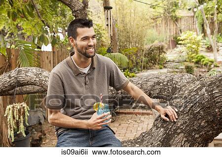 Man sitting on branch in garden having a drink View Large Photo Image Stock Image - Man sitting on branch in garden having a drink. Fotosearch