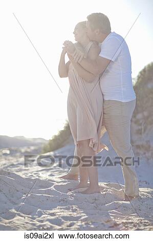 Stock Image - Mature couple hugging on beach. Fotosearch