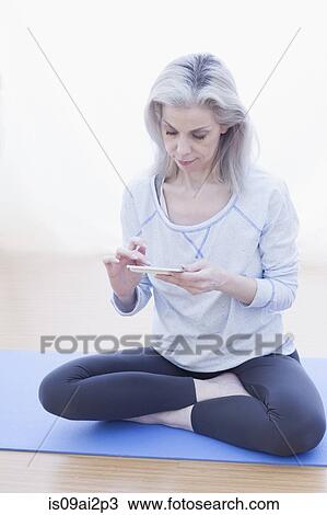 Mature woman in lotus pose using cellular phone View Large Photo Image Stock Image - Mature woman in lotus pose using cellular phone. Fotosearch