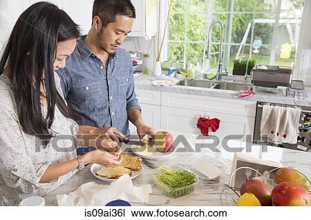 Mid adult couple preparing sandwich at kitchen counter View Large Photo Image Stock Image - Mid adult couple preparing sandwich at kitchen counter. Fotosearch