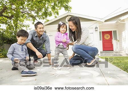 Mid adult couple with two children drawing on paving slabs View Large Photo Image Stock Image - Mid adult couple with two children drawing on paving slabs. Fotosearch