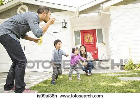 Mid adult couple with two children blowing bubbles View Large Photo Image Stock Image - Mid adult couple with two children blowing bubbles. Fotosearch