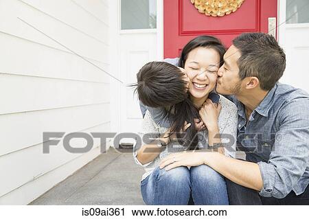 Stock Image - Mid adult couple with young son on porch. Fotosearch