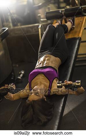 Mid Adult Woman Doing Abdominal Exercise On Weight Bench Stock