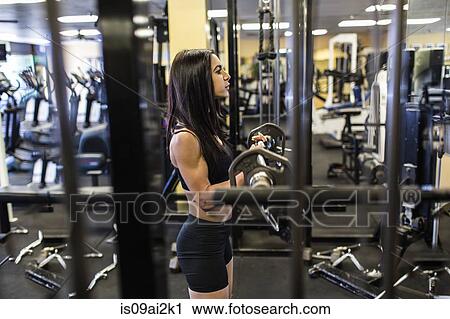 Mid adult woman weightlifting barbell in gym View Large Photo Image Stock Image - Mid adult woman weightlifting barbell in gym. Fotosearch