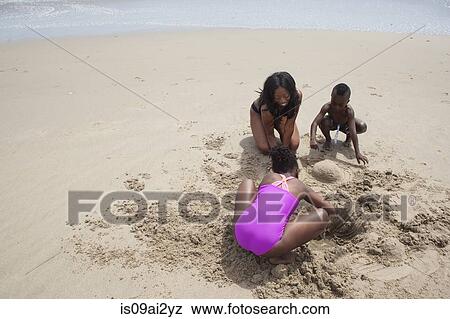Mother and children digging in sand on beach View Large Photo Image Stock Photo - Mother and children digging in sand on beach. Fotosearch