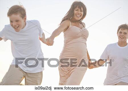 Stock Image - Mother and two sons, holding hands, outdoors. Fotosearch