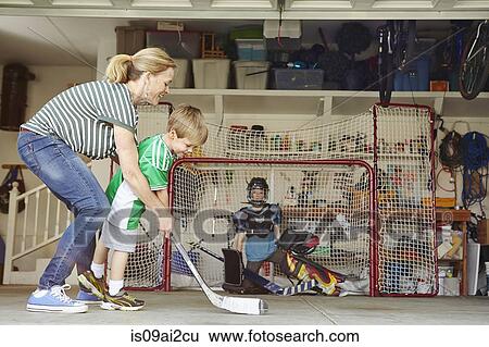 Mother playing hockey in garage with two sons View Large Photo Image Stock Photograph - Mother playing hockey in garage with two sons. Fotosearch