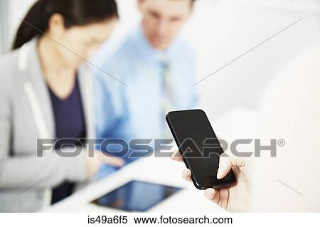 Person using smartphone, colleagues in background View Large Photo Image Stock Photography - Person using smartphone, colleagues in background. Fotosearch