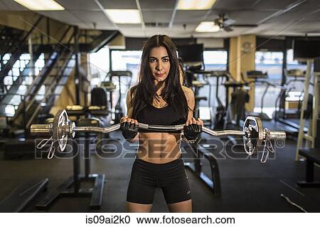 Stock Image - Portrait of mid adult woman weightlifting in gym. Fotosearch