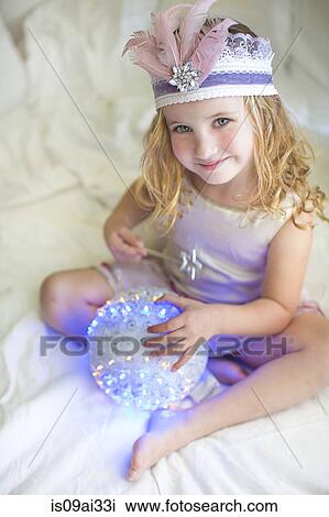 Stock Image - Portrait of young girl in fairy costume on bed. Fotosearch
