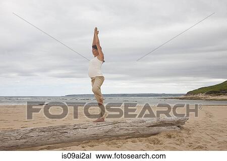 Pregnant mid adult woman practicing yoga on tree trunk at beach View Large Photo Image Stock Image - Pregnant mid adult woman practicing yoga on tree trunk at beach. Fotosearch