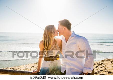 Stock Image - Romantic young couple sharing a kiss at coast. Fotosearch