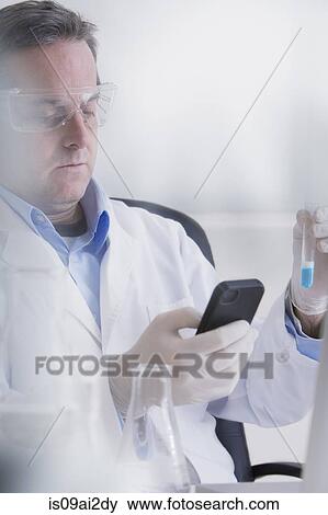 Stock Photo - Scientist holding smartphone and test tube. Fotosearch