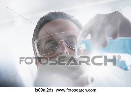 Stock Photograph - Scientist pouring liquid into test tube. Fotosearch