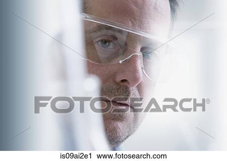 Stock Image - Scientist wearing protective goggles, close-up. Fotosearch