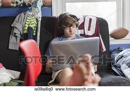 Teenage boy sitting on chair using laptop computer View Large Photo Image Stock Image - Teenage boy sitting on chair using laptop computer. Fotosearch