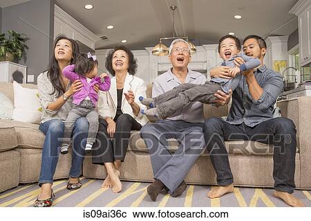 Stock Image - Three generation family playing together on sofa. Fotosearch