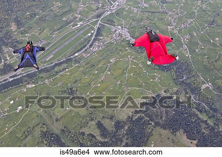 Two men flying above fields in wingsuits View Large Photo Image Picture - Two men flying above fields in wingsuits. Fotosearch
