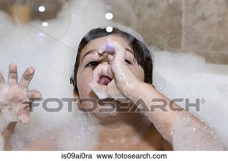 Stock Image - Young boy blowing bubbles in bubble bath. Fotosearch