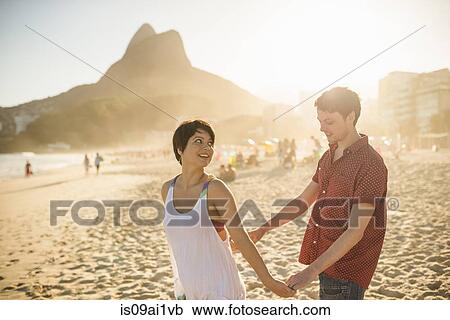 Stock Image - Young couple enjoying sunset, Ipanema Beach, Rio, Brazil. Fotosearch