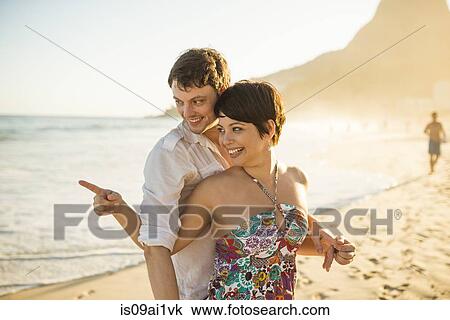 Stock Image - Young couple enjoying sunset, Ipanema Beach, Rio, Brazil. Fotosearch