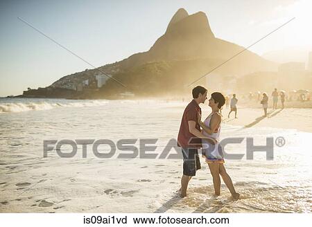 Stock Image - Young couple hugging at sunset, Ipanema Beach, Rio, Brazil. Fotosearch