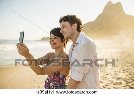 Stock Image - Young couple self-photographing, Ipanema Beach, Rio, Brazil. Fotosearch