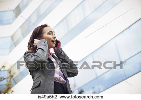Young female businesswoman talking on smartphone outside office View Large Photo Image Stock Image - Young female businesswoman talking on smartphone outside office. Fotosearch