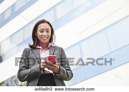 Young female businesswoman texting on smartphone outside office View Large Photo Image Stock Image - Young female businesswoman texting on smartphone outside office. Fotosearch