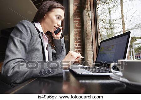 Stock Photo - Young female businesswoman using laptop and smartphone in cafe. Fotosearch