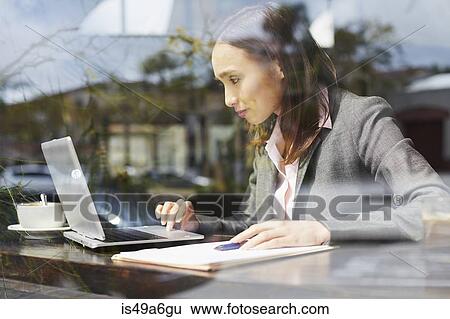 Stock Photograph - Young female businesswoman using laptop in cafe. Fotosearch