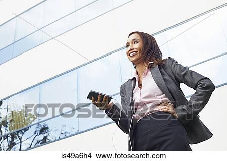 Young female businesswoman using smartphone outside office View Large Photo Image Picture - Young female businesswoman using smartphone outside office. Fotosearch