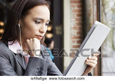 Young female businesswoman with earphones reading paperwork in cafe View Large Photo Image Stock Photo - Young female businesswoman with earphones reading paperwork in cafe. Fotosearch