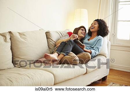 Young female couple reclining on sofa looking at digital tablet View Large Photo Image Stock Photography - Young female couple reclining on sofa looking at digital tablet. Fotosearch
