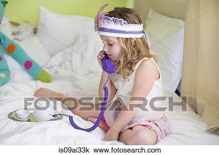 Young girl playing with toy telephone on bed View Large Photo Image Stock Image - Young girl playing with toy telephone on bed. Fotosearch