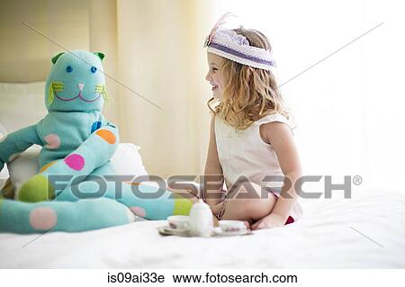 Young girl sharing tea with cuddly toy on bed View Large Photo Image Stock Image - Young girl sharing tea with cuddly toy on bed. Fotosearch