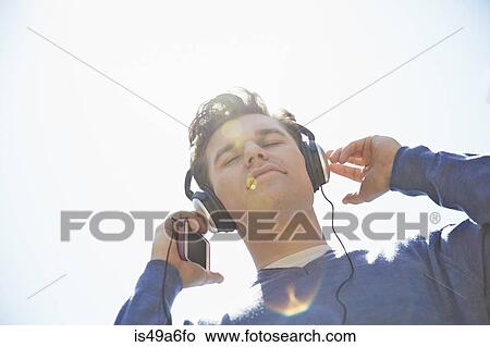 Young man wearing headphones listening to music View Large Photo Image Picture - Young man wearing headphones listening to music. Fotosearch