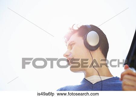 Young man wearing headphones listening to music View Large Photo Image Stock Photography - Young man wearing headphones listening to music. Fotosearch