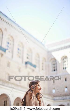 Picture - Young woman gazing upward in historic courtyard. Fotosearch