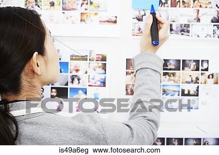 Young woman looking at photographs holding pen View Large Photo Image Stock Image - Young woman looking at photographs holding pen. Fotosearch