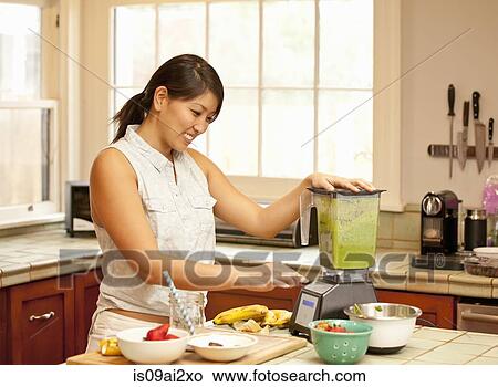 Young woman making green smoothie in kitchen View Large Photo Image Picture - Young woman making green smoothie in kitchen. Fotosearch