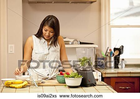 Young woman making green smoothie in kitchen View Large Photo Image Stock Photograph - Young woman making green smoothie in kitchen. Fotosearch